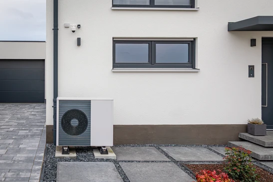 Extérieur résidentiel moderne avec deux unités de pompe à chaleur air-eau installées sur socles béton