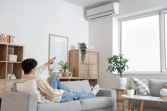 Technicien en combinaison de travail effectuant la maintenance d'une unité de climatisation murale dans un environnement intérieur