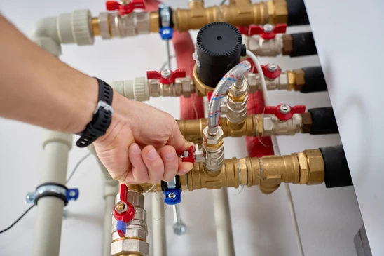 Technicien en tenue professionnelle Riemer diagnostiquant un problème de chauffage en intérieur résidentiel : il utilise un appareil de diagnostic thermique ou un multimètre pour tester une installation défaillante, peut-être un radiateur ou un système qui ne fonctionne pas correctement. La scène montre l'expertise technique et la réactivité de dépannage, dans un contexte urgent mais maîtrisé. L'environnement doit être un domicile client, l'équipement défaillant clairement visible, mettant l'accent sur le diagnostic professionnel plutôt que sur l'installation ou la maintenance préventive.